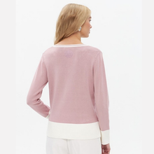 Load image into Gallery viewer, A woman shown from the back wearing a light pink knit sweater with contrasting white trim at the crew neck, cuffs, and hem, paired with white pants against a plain white background.