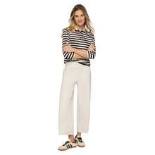 Load image into Gallery viewer, Woman wearing a black and white striped shirt with white pants on a white background