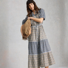 Load image into Gallery viewer, Woman wearing a patterned dress holding a woven bag against a plain background