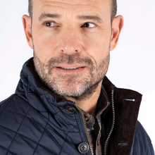 Load image into Gallery viewer, Man wearing a navy quilted jacket with a white background