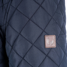 Load image into Gallery viewer, Quilted blue jacket with a brand logo patch on a white background