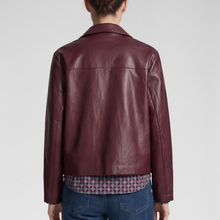 Load image into Gallery viewer, A person shown from the back wearing a cropped, long-sleeve leather jacket in a deep burgundy color, paired with a patterned shirt and blue jeans against a light gray studio background.