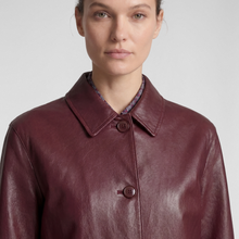Load image into Gallery viewer, A close-up of a model wearing a burgundy leather jacket with a pointed collar and two front buttons, set against a plain light gray background.