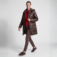 Load image into Gallery viewer, A woman modeling a dark brown quilted hooded puffer jacket over a red top and brown pants, walking against a light gray studio background.