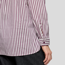 Load image into Gallery viewer, Close-up of a person wearing a striped shirt with rolled-up sleeves on a plain background