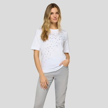 Load image into Gallery viewer, Woman wearing a white t-shirt with black speckles and gray pants on a light gray background