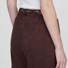 Load image into Gallery viewer, Close-up of a model wearing dark brown wide-leg trousers with a matching brown woven belt, paired with a white ribbed top against a light gray background.