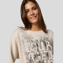 Load image into Gallery viewer, Woman wearing a beige sweater with text design on a plain background