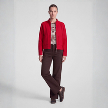 Load image into Gallery viewer, A model stands against a light gray studio background wearing a bright red cropped jacket over a black-and-white patterned top, dark brown trousers, and dark brown shoes.