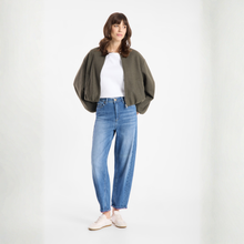 Load image into Gallery viewer, Woman wearing a green cardigan, white shirt, and blue jeans on a white background