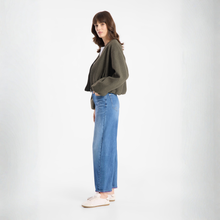 Load image into Gallery viewer, Woman wearing a green sweater and blue jeans on a white background