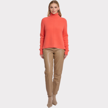 Load image into Gallery viewer, Woman wearing a coral turtleneck sweater and brown pants on a white background