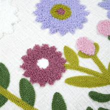 Load image into Gallery viewer, Close-up of a white woven textile with colorful floral embroidery, including purple, pink, green, and mauve flowers.