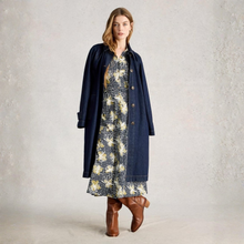 Load image into Gallery viewer, Woman wearing a long navy coat over a floral dress with brown boots on a light gray background