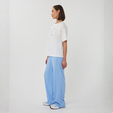 Load image into Gallery viewer, Woman wearing a white t-shirt and blue striped pants on a plain background