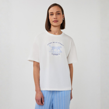 Load image into Gallery viewer, Woman wearing a white t-shirt with a graphic design on a plain background