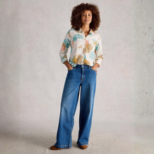 Load image into Gallery viewer, Woman wearing a floral blouse and blue jeans against a plain background