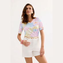 Load image into Gallery viewer, Woman wearing a colorful tie-dye top and white shorts on a light background