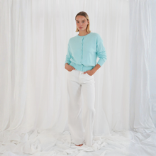 Load image into Gallery viewer, Person wearing a light blue cardigan and white pants against a white background