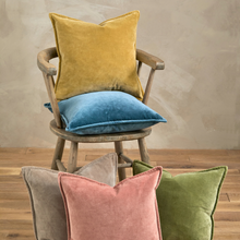 Load image into Gallery viewer, Chair with colorful velvet cushions against a neutral wall.