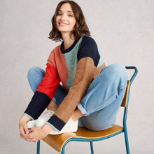 Load image into Gallery viewer, Woman sitting on a chair wearing a colorful sweater and jeans against a plain background