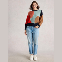 Load image into Gallery viewer, Woman wearing a colorful sweater and light blue jeans on a plain background