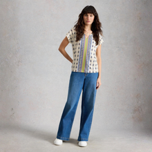 Load image into Gallery viewer, Woman wearing a patterned top and blue jeans against a plain background