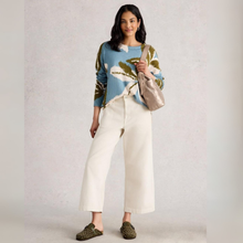 Load image into Gallery viewer, Woman wearing a patterned sweater and white pants, holding a beige handbag against a plain background