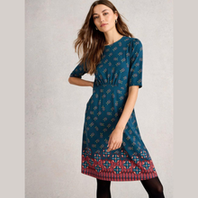 Load image into Gallery viewer, Woman wearing a blue patterned dress on a light gray background