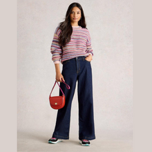 Load image into Gallery viewer, Woman wearing a striped sweater and blue jeans, holding a red handbag against a plain background
