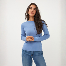 Load image into Gallery viewer, A woman modeling a light blue long-sleeve knit sweater with a crew neck, paired with blue jeans, against a plain white studio background.
