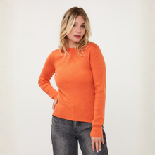 Load image into Gallery viewer, A woman modeling a bright orange crewneck knit sweater with tiny speckled details, paired with dark gray jeans, against a plain off-white background.

