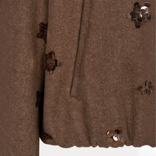 Load image into Gallery viewer, Close-up of a brown textured garment, likely a coat or jacket, featuring decorative sequined flower appliqués and a side seam detail.
