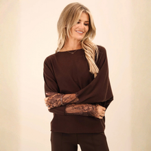 Load image into Gallery viewer, Model is wearing chocolate brown knitted top with lace detailed sleeves with matching brown trousers on a beige background. 

