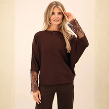 Load image into Gallery viewer, Model is wearing chocolate brown knitted top with lace detailed sleeves with matching brown trousers on a beige background. 
