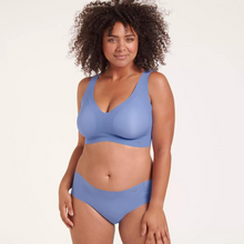 Load image into Gallery viewer, A model wearing the Sloggi Zero Feel Bra and Hipster in Riviera Blue.

