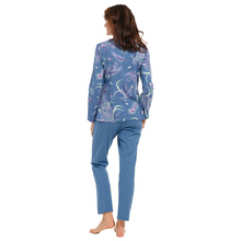 Load image into Gallery viewer, Female model wearing pyjamas with a paisley and peacock feather design on top and blue bottoms away from the camera
