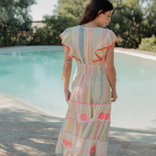 Load image into Gallery viewer, Woman in a colorful dress standing by a pool with trees in the background
