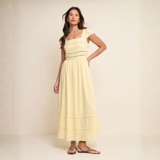 Woman wearing a light yellow dress against a beige background
