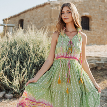 Load image into Gallery viewer, Woman wearing a green dress with colorful accents in a rustic outdoor setting
