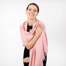Load image into Gallery viewer, A smiling woman with her hair pulled back wears a soft pink shawl draped over her shoulders and black clothing, photographed against a clean white studio background.
