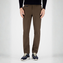Load image into Gallery viewer, A person wearing slim-fit brown trousers, a black long-sleeve top, and navy sneakers, standing against a light gray studio background.
