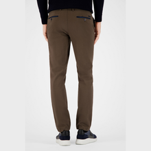 Load image into Gallery viewer, A person shown from the back wearing slim-fit brown trousers with dark blue pocket details, a black long-sleeve top, and navy sneakers against a light gray studio background.
