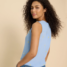 Load image into Gallery viewer, female model wearing whitestuff sleeveless shirt in blue print with hands in pockets
