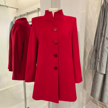 Load image into Gallery viewer, A bright red longline coat with a high stand collar and four large decorative buttons, displayed on a mannequin in a clothing store. A second view of the same coat appears in the background on a rack.
