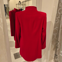 Load image into Gallery viewer, A bright red structured blazer displayed on a mannequin torso in a boutique setting, with a mirror reflecting the back of the garment.
