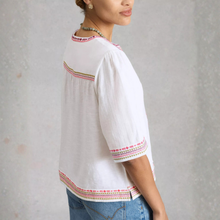 Load image into Gallery viewer, Woman wearing a white blouse with colorful embroidery on a plain background
