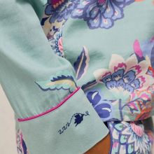 Load image into Gallery viewer, Close-up of a floral long-sleeve top or dress in mint green with a pink piped cuff and embroidered script on the sleeve, set against a matching multicolor floral pattern.

