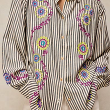 Load image into Gallery viewer, A close-up of a long-sleeve button-up shirt with vertical black and beige stripes, decorated with colorful embroidered floral and paisley motifs in purple, blue, yellow, and green.
