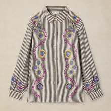 Load image into Gallery viewer, A long-sleeve button-up shirt with vertical black and beige stripes, decorated with colorful embroidered floral and vine motifs in pink, blue, yellow, and green, laid flat against a light beige background.
